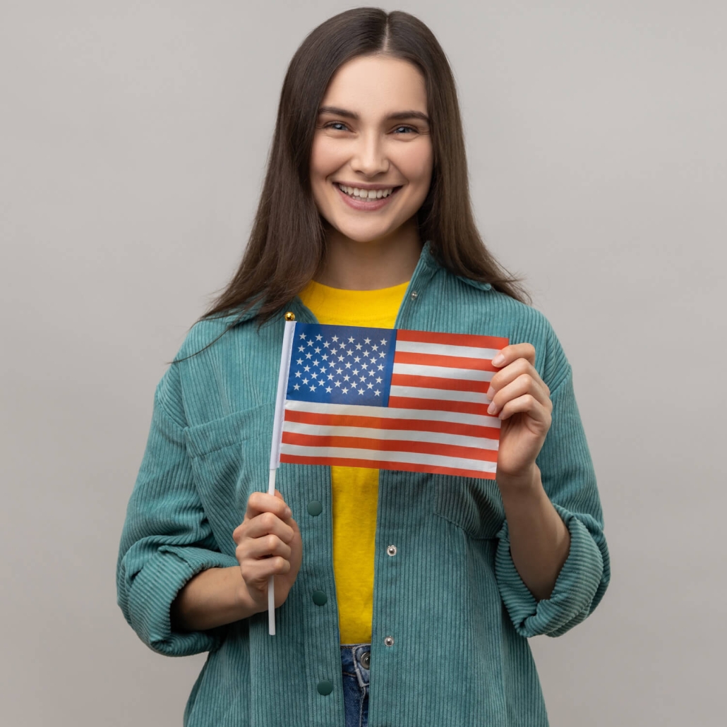 A young lady holding the American flag representing immigration law and the happiness of having a green card or citizenship